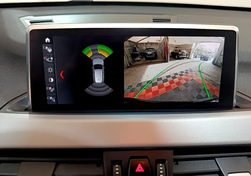 Écran tactile du tableau de bord BMW X1 noir 2020 affichant caméra de recul et capteurs de stationnement.