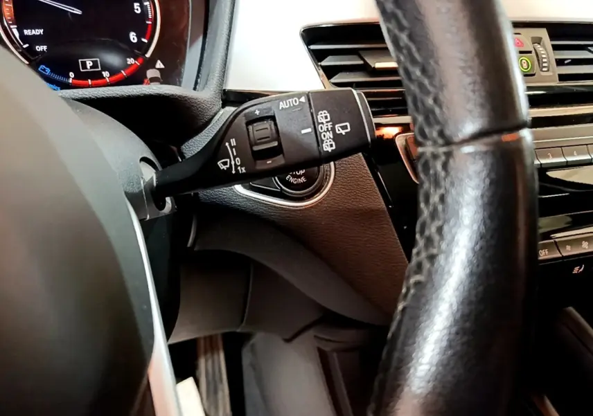 Gros plan sur le commodo d’essuie-glace côté gauche du tableau de bord noir du BMW X1 2020 sDrive16d Business Design.