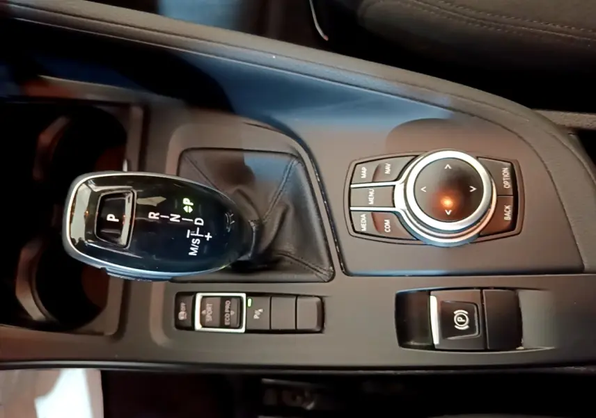 Gros plan sur la console centrale noire du BMW X1 2020 avec levier de vitesses automatique et molette de contrôle multimédia.