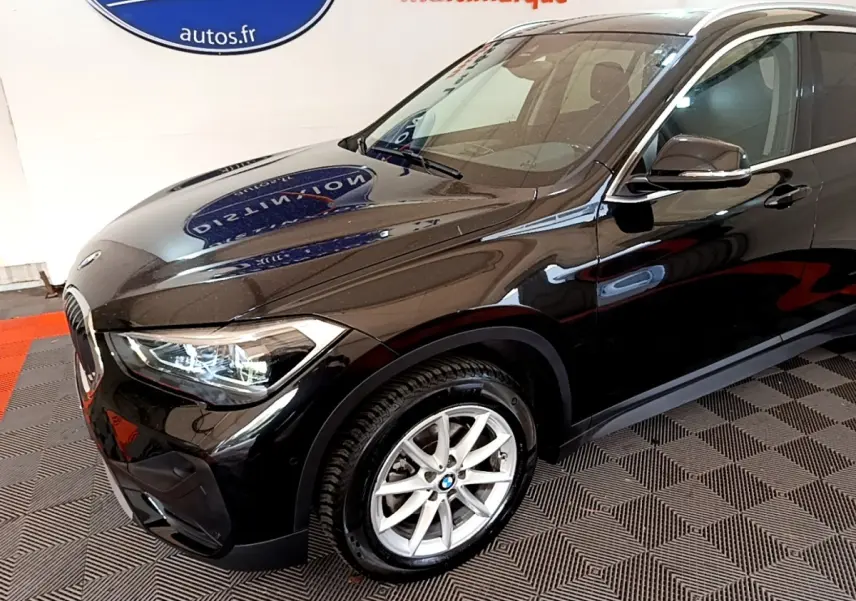 BMW X1 noir vue 3/4 avant droit mettant en valeur ses phares LED et jantes alliage argentées.