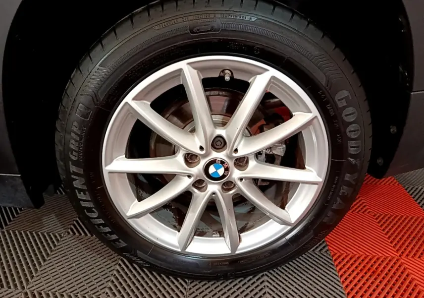 Gros plan sur la jante alliage argentée avec logo BMW centrale, montée sur pneu Goodyear, sur BMW X1 noir.