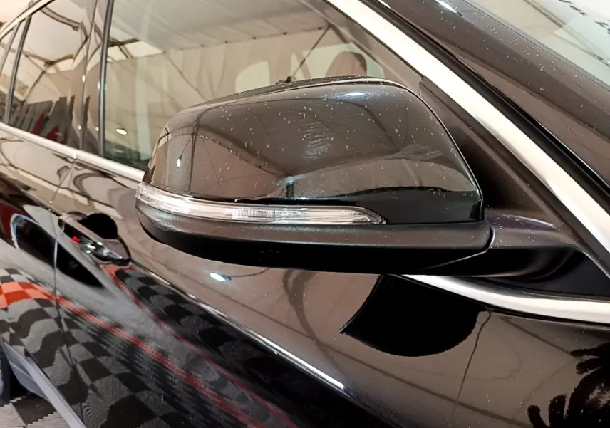 Gros plan sur le rétroviseur côté gauche noir brillant de la BMW X1 sDrive16d Business Design 2020.