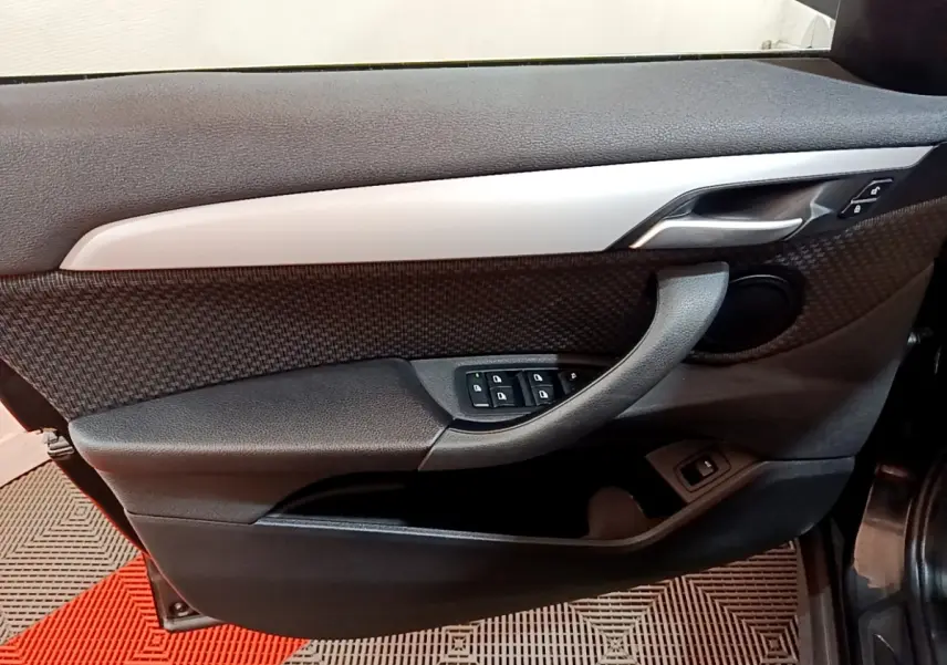 Détail de la porte côté conducteur noire du BMW X1 2020 avec commandes de vitres et poignée intégrée.