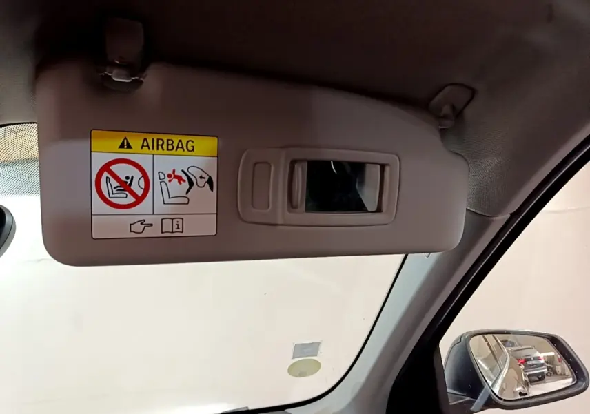 Détail du pare-soleil beige avec miroir et avertissement airbag, côté conducteur intérieur d’un BMW X1 noir 2020.