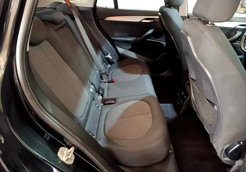 Vue intérieure côté gauche sur la banquette arrière noire du BMW X1 sDrive16d Business Design 2020.