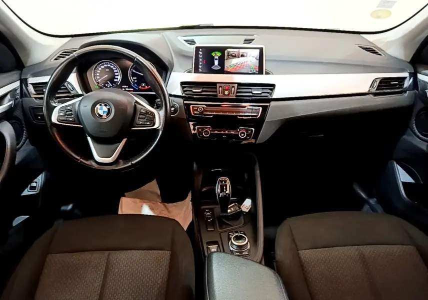 Intérieur BMW X1 2020 vu de face, tableau de bord noir avec écran tactile et volant cuir multifonctions.
