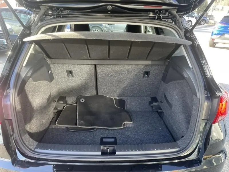 Coffre ouvert vu de l'arrière d'une SEAT Arona noire 2023, tapis de sol noir à l'intérieur, espace de rangement visible.