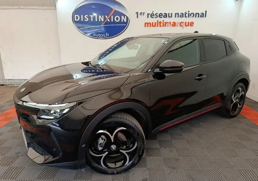 Vue 3/4 avant droit d'une Alfa Romeo Junior 1.2 hybride noire avec jantes noires et détails rouges sur le bas de caisse.