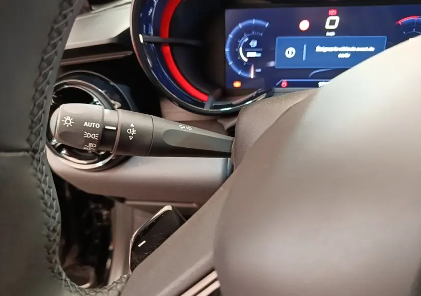 Gros plan sur le combiné d'instruments numérique avec éclairage rouge et levier de commande des phares sur l'Alfa Romeo Junior 2024.