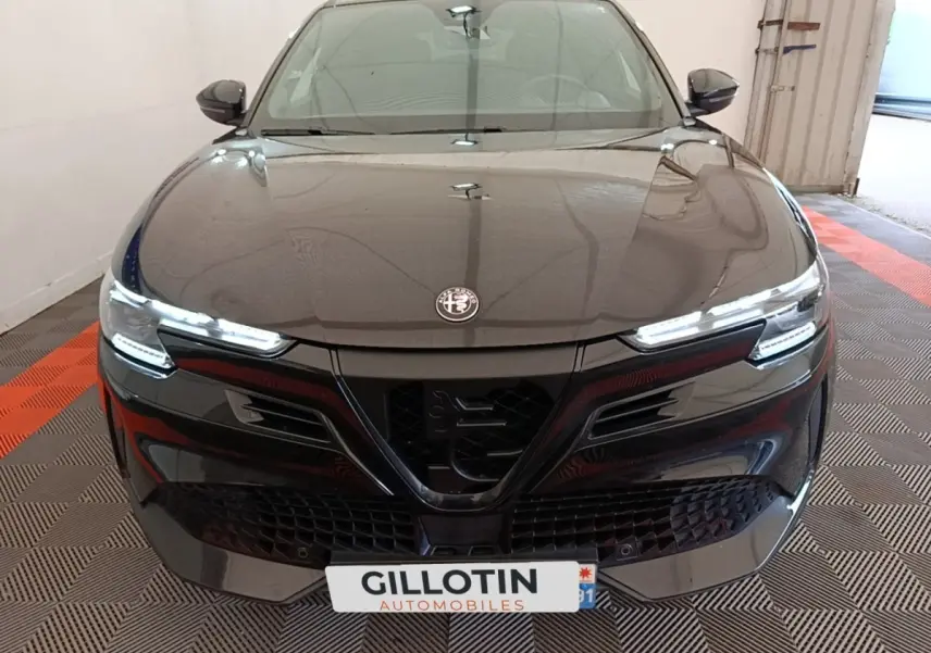 Vue avant d'une Alfa Romeo Junior 1.2 Ibrida noire avec phares LED et calandre distinctive en V.