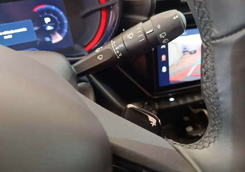 Gros plan intérieur sur le levier de commande des essuie-glaces et le volant noir de l'Alfa Romeo Junior 2024.
