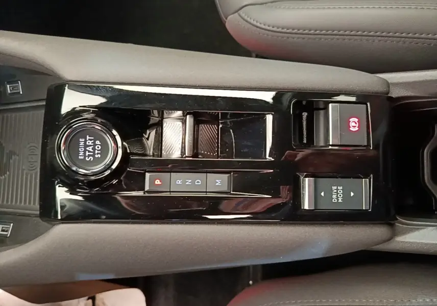 Vue plongeante sur la console centrale noire de l'Alfa Romeo Junior 2024, avec bouton start/stop et commandes boîte auto.