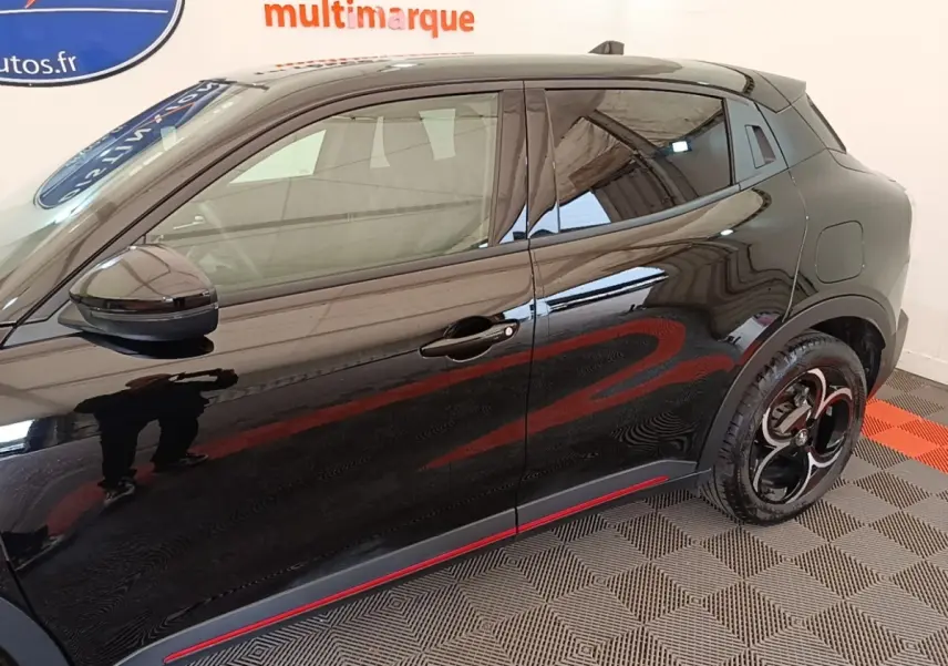 Vue de profil côté gauche de l'Alfa Romeo Junior noire avec jantes noires et détails rouges sur bas de caisse.