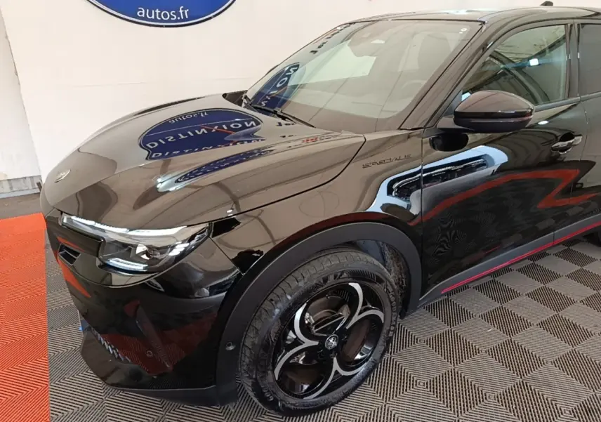 Vue 3/4 avant droit d'une Alfa Romeo Junior noire avec jantes noires et détails rouges sur les bas de caisse.
