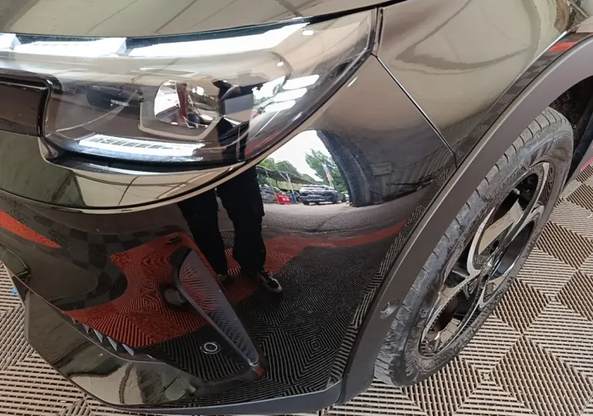 Gros plan sur l'aile avant droite noire d'une Alfa Romeo Junior 2024, mettant en valeur le phare LED et la jante noire.