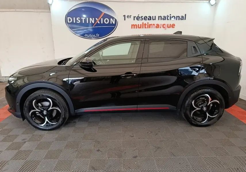 Vue de profil côté gauche d'une Alfa Romeo Junior 1.2 Ibrida noire avec jantes noires et détails rouges sur les bas de caisse.