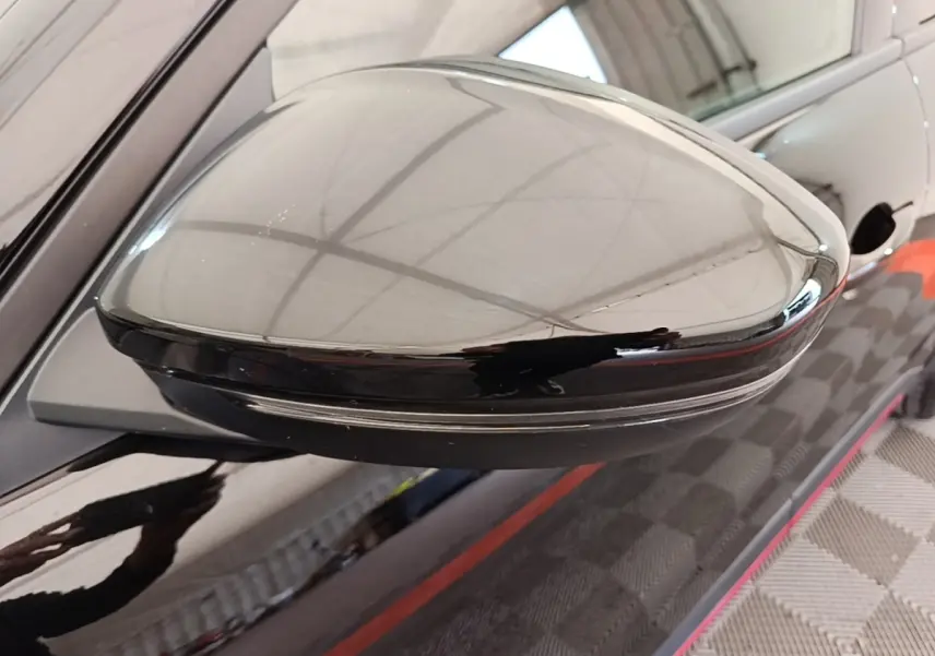 Rétroviseur côté gauche noir brillant de l'Alfa Romeo Junior 1.2 Ibrida 136ch Speciale DCT6 2024, reflet de l'environnement intérieur.