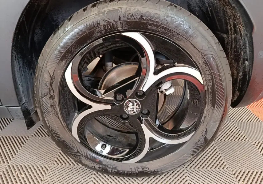 Gros plan sur la roue avant droite noire avec jante en alliage bicolore au design en trois branches d'Alfa Romeo Junior.
