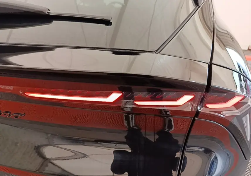 Gros plan sur le feu arrière droit allumé d'une Alfa Romeo Junior noire, avec reflet brillant sur la carrosserie.