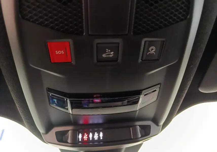 Vue en gros plan du panneau de commandes au plafond de l'Alfa Romeo Junior 1.2 Ibrida, avec bouton SOS rouge et éclairage des ceintures.