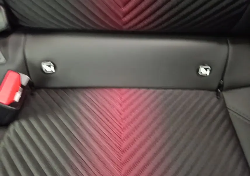 Gros plan sur la banquette arrière noire de l'Alfa Romeo Junior 1.2 Ibrida avec fixation Isofix et ceinture rouge visible.