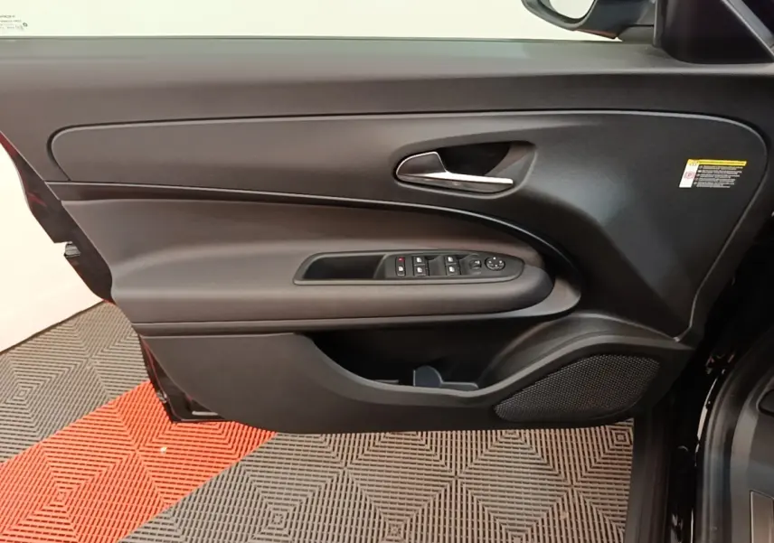 Vue rapprochée de la porte avant gauche noire de l'Alfa Romeo Junior 2024 avec commandes électriques et poignée argentée.