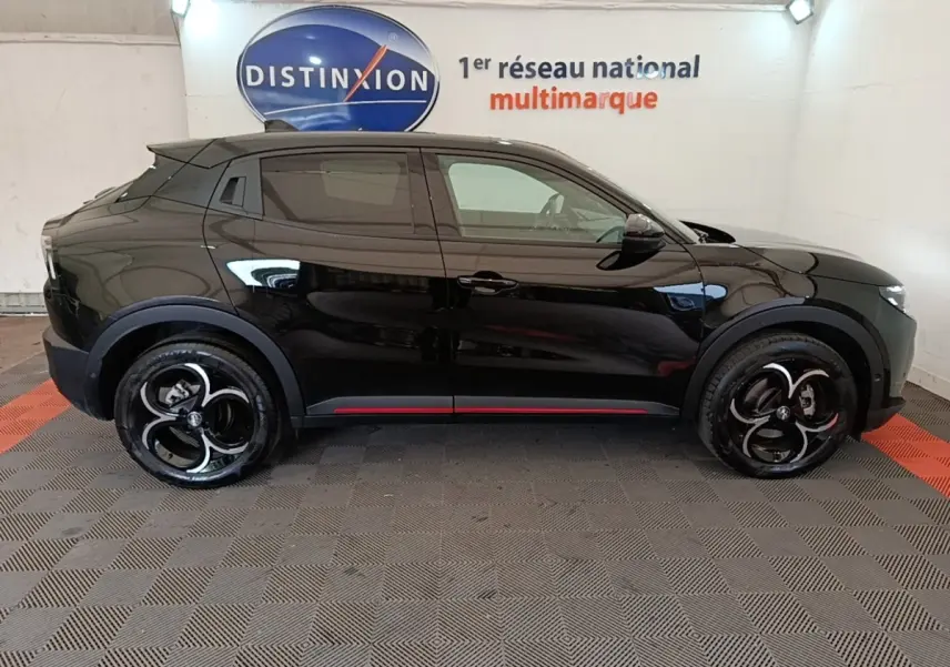 Vue de profil côté gauche d'une Alfa Romeo Junior noire avec jantes noires et détails rouges sur le bas de caisse.