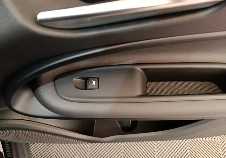 Détail de la poignée intérieure côté gauche de la porte d’une Alfa Romeo Junior 1.2 Ibrida noire, avec bouton de verrouillage.