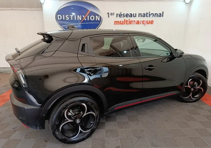 Vue latérale droite d'une Alfa Romeo Junior noire 2024 avec jantes noires et détails rouges sur bas de caisse.