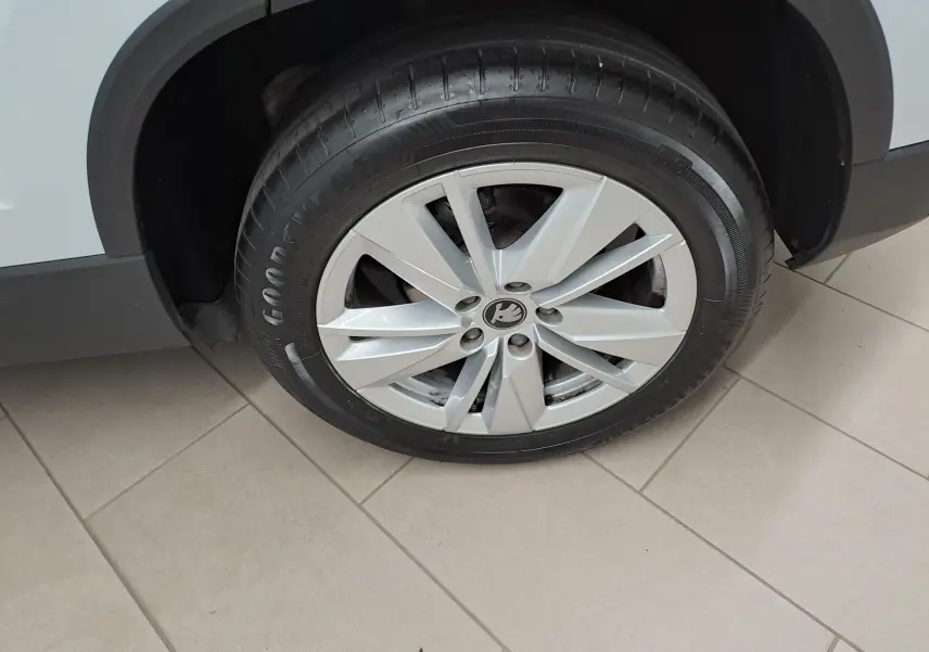 Gros plan sur la roue avant droite d’un Skoda Karoq blanc lune, mettant en valeur la jante alliage et le pneu Goodyear.