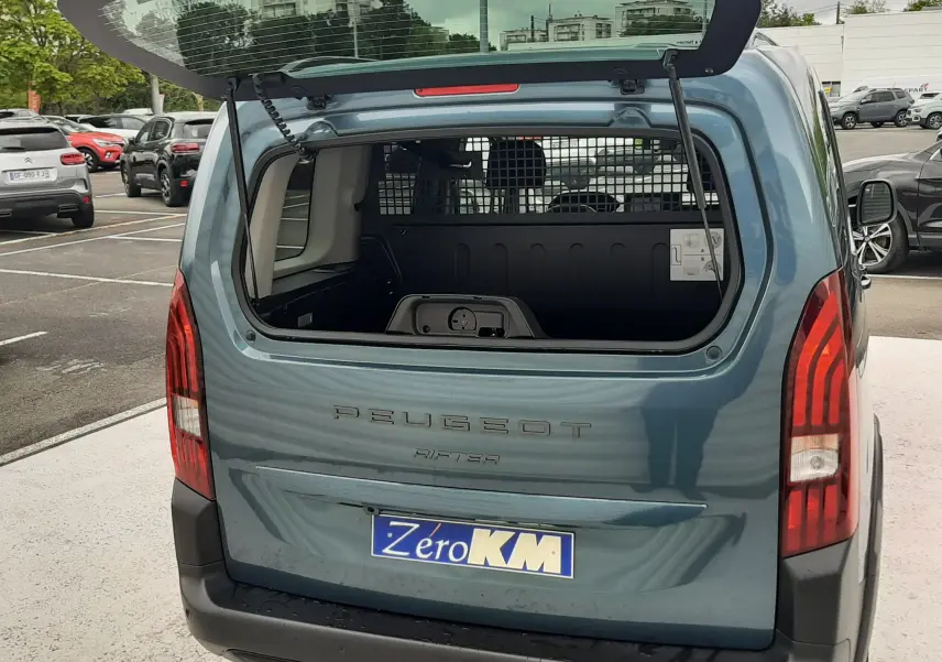 Vue arrière du Peugeot Rifter bleu Kiama 2026 avec hayon ouvert, montrant l'espace de chargement et la grille de séparation.