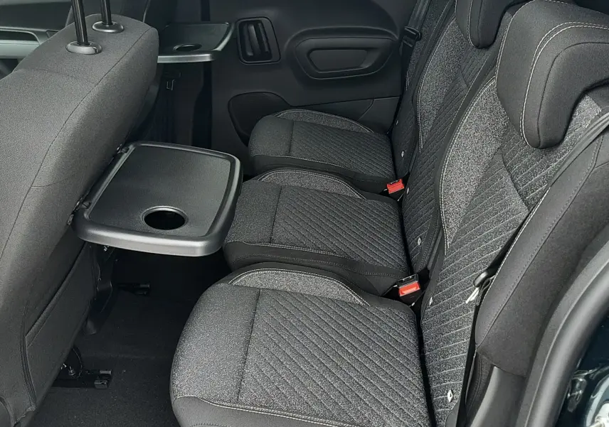 Vue latérale intérieure des sièges arrière en tissu gris du Peugeot Rifter Bleu Kiama avec tablette rabattable intégrée.