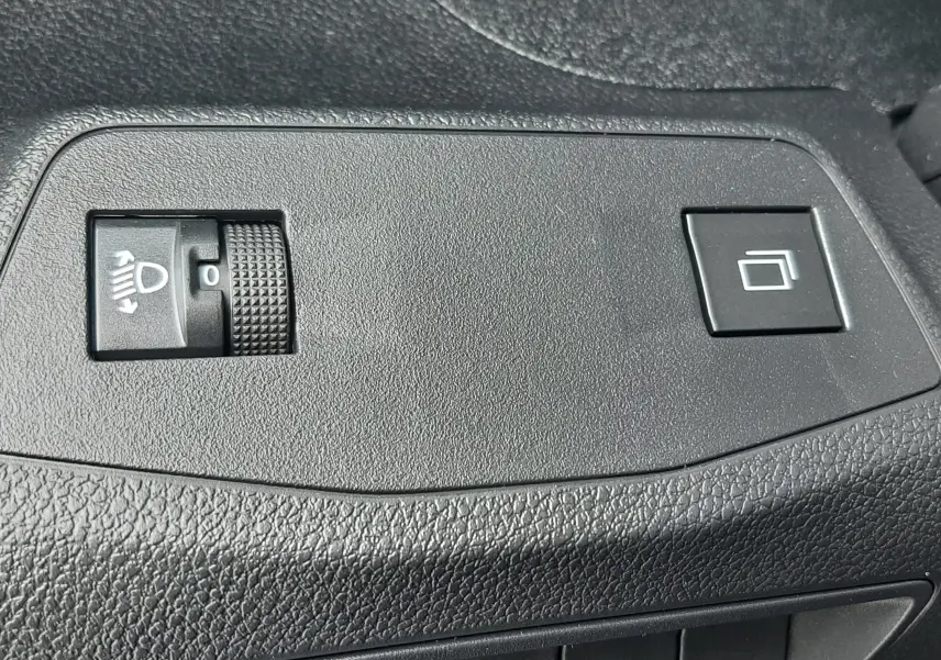 Gros plan sur les commandes de réglage des phares et bouton de fonction sur la porte intérieure du Peugeot Rifter bleu Kiama 2026.