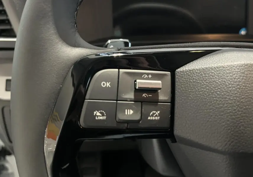 Gros plan sur les commandes à gauche du volant en cuir noir du Peugeot Expert Fourgon blanc 2024.
