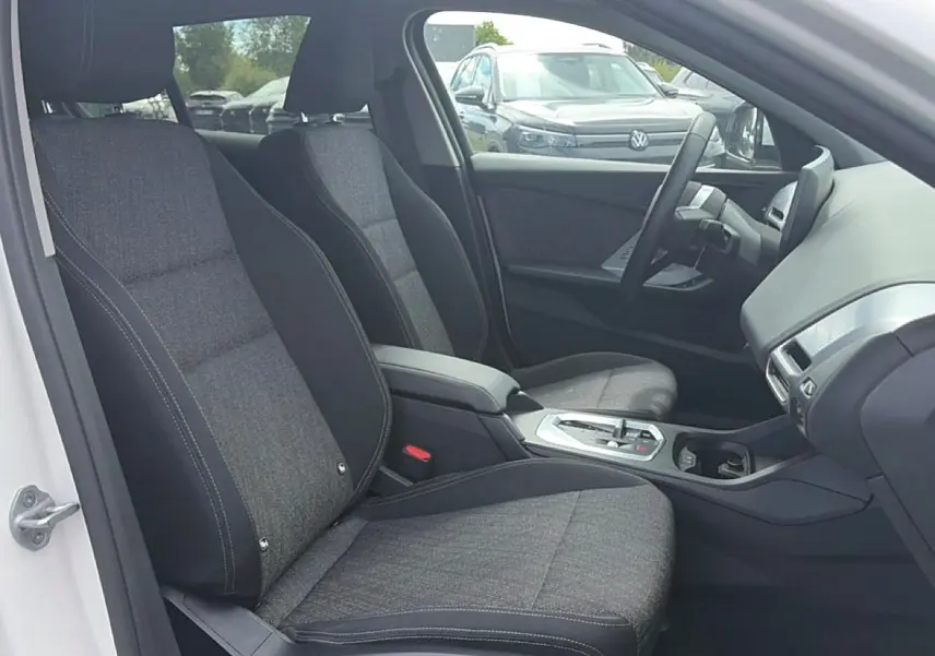 Vue intérieure côté conducteur de la BMW Série 1 blanche avec sièges sport gris et console centrale moderne.