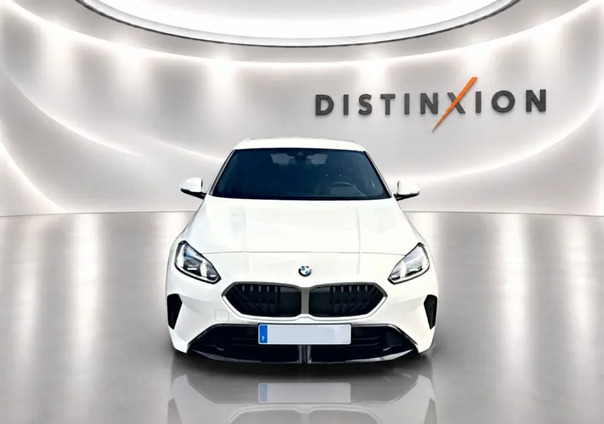 BMW Série 1 blanche vue de face, avec calandre noire et logo BMW sur fond lumineux studio Distinxion.