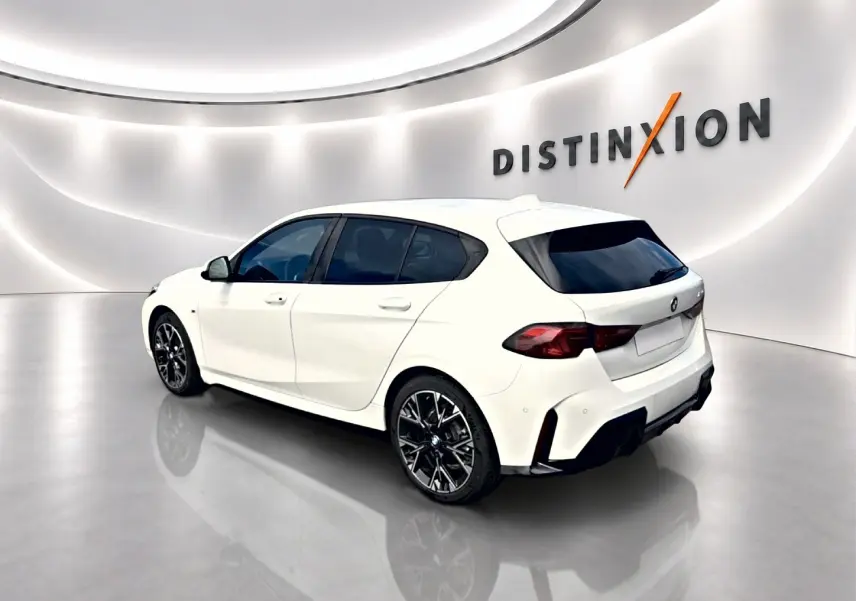BMW Série 1 blanche vue en 3/4 arrière droit dans un showroom avec jantes alu noires et vitres teintées.