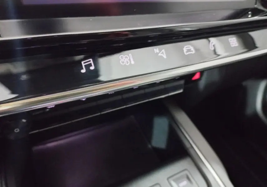 Gros plan sur la console centrale noire du Citroën C5 Aircross avec commandes tactiles éclairées en blanc.