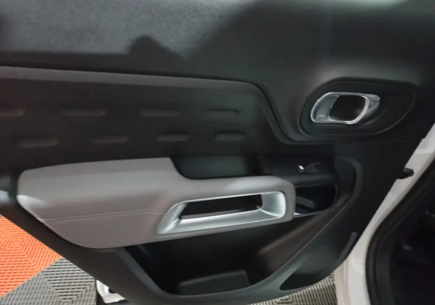 Gros plan sur la porte intérieure côté droit du Citroën C5 Aircross blanc, avec poignée argentée et garniture noire et grise.