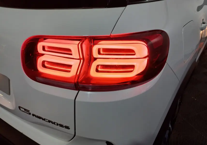 Gros plan sur le feu arrière droit allumé d'un Citroën C5 Aircross blanc, avec logo visible sur le hayon.
