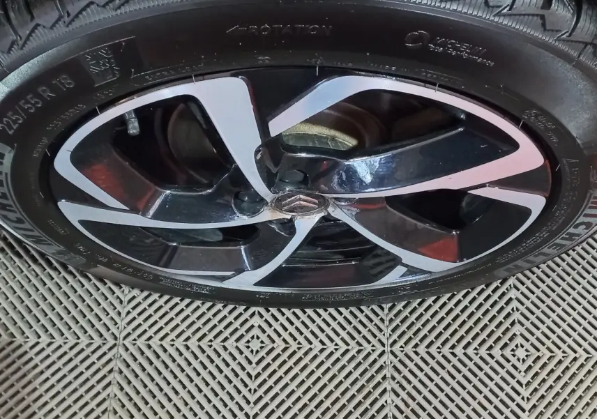 Gros plan sur la jante noire et argentée avec logo Citroën au centre d’un pneu Michelin monté sur un C5 Aircross blanc.