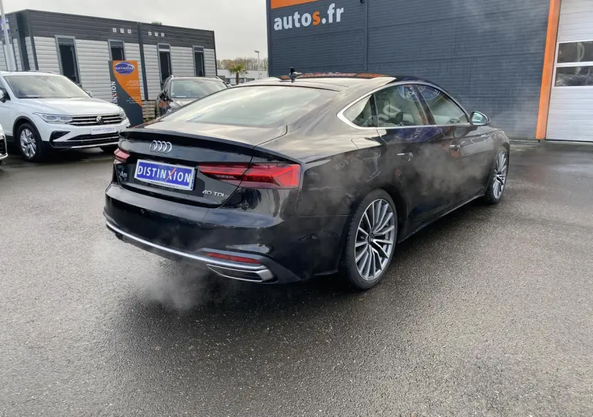 Audi A5 Sportback noir mythic métallisé vue 3/4 arrière droit avec jantes multibranches et échappement visible