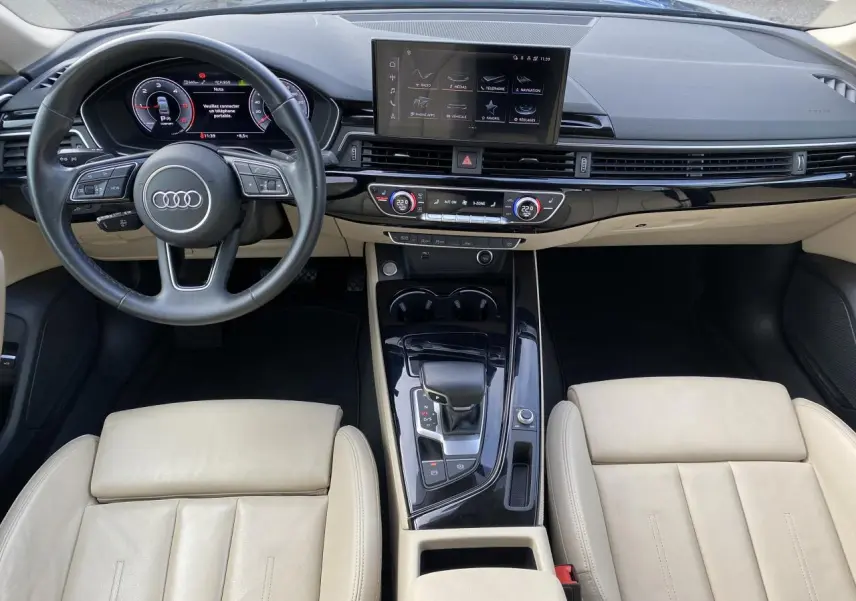 Vue intérieure de l'Audi A5 Sportback 2022 montrant tableau de bord noir brillant et sièges cuir beige clair.
