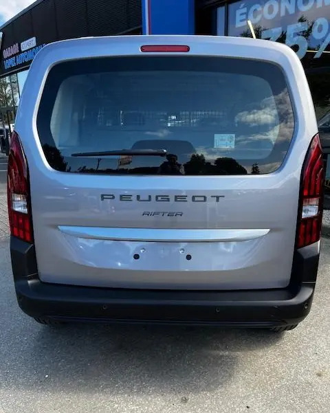 Vue arrière d'un Peugeot Rifter gris foncé 2024 avec hayon vitré et feux arrière verticaux rouges.