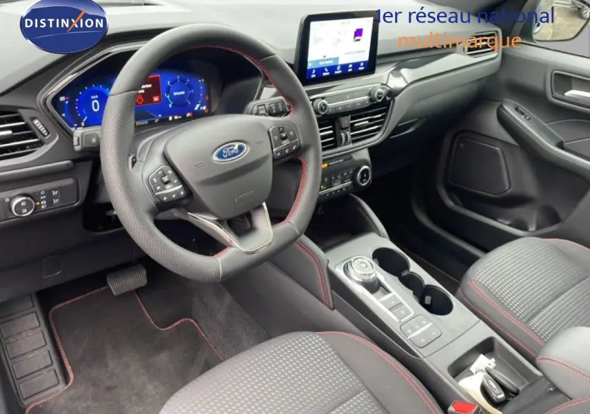 Vue intérieure côté conducteur du Ford Kuga 2024, volant cuir noir avec surpiqûres rouges et écran tactile central.