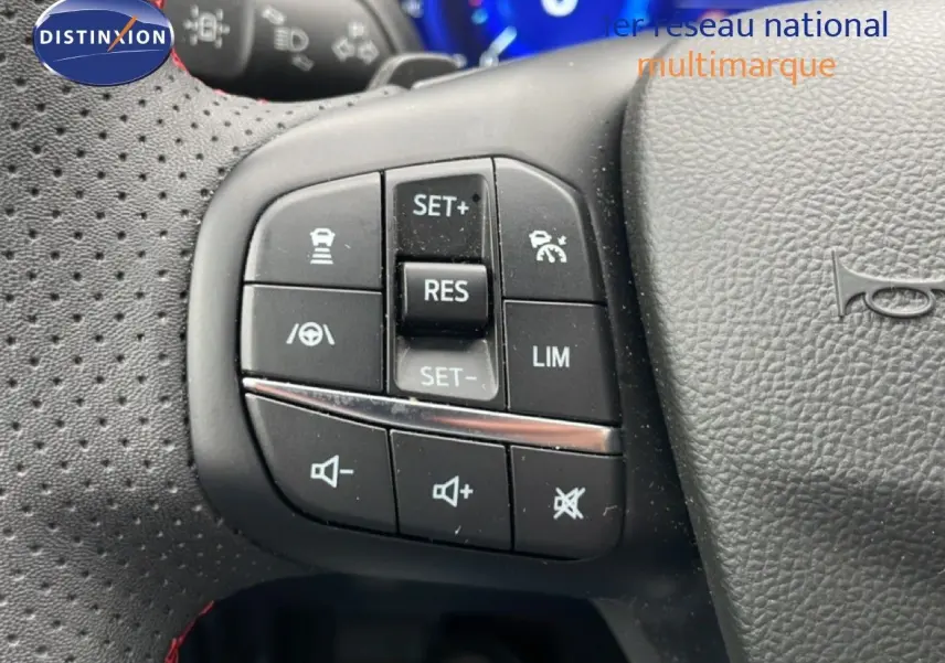 Gros plan sur les commandes de régulateur et volume au volant perforé noir du Ford Kuga bleu Vapor Metal 2024.