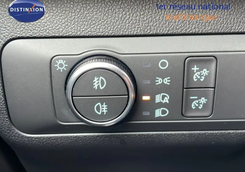 Gros plan sur le bouton de commande des feux d’un Ford Kuga 2024 bleu vapor metal, avec réglage des phares activé.