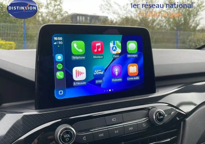 Écran tactile central du Ford Kuga 2024 affichant les applications connectées, avec tableau de bord en finition carbone.