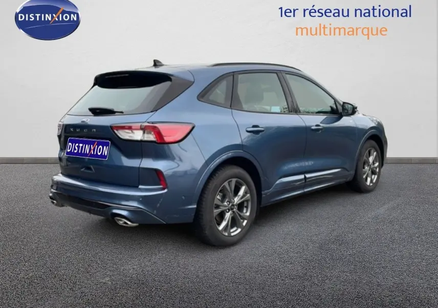 Ford Kuga 2024 bleu Vapor Metal en 3/4 arrière droit, finition ST-LINE avec jantes alliage et double sortie d’échappement.