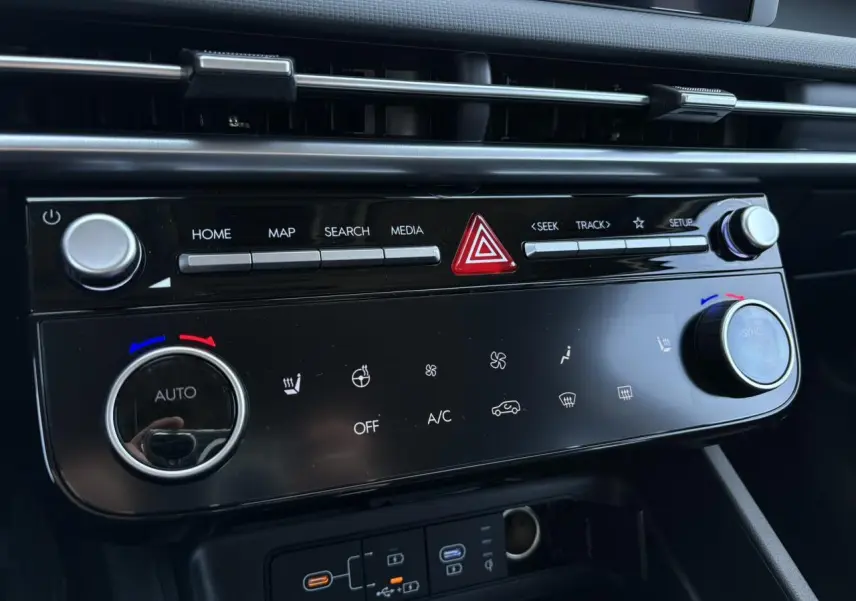 Gros plan sur la console centrale noire brillante du Hyundai Tucson 2025 avec commandes climatisation et multimédia.